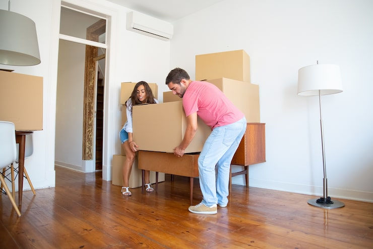 young-hispanic-couple-moving-into-new-apartment-carrying-carton-boxes-furniture_74855-1046