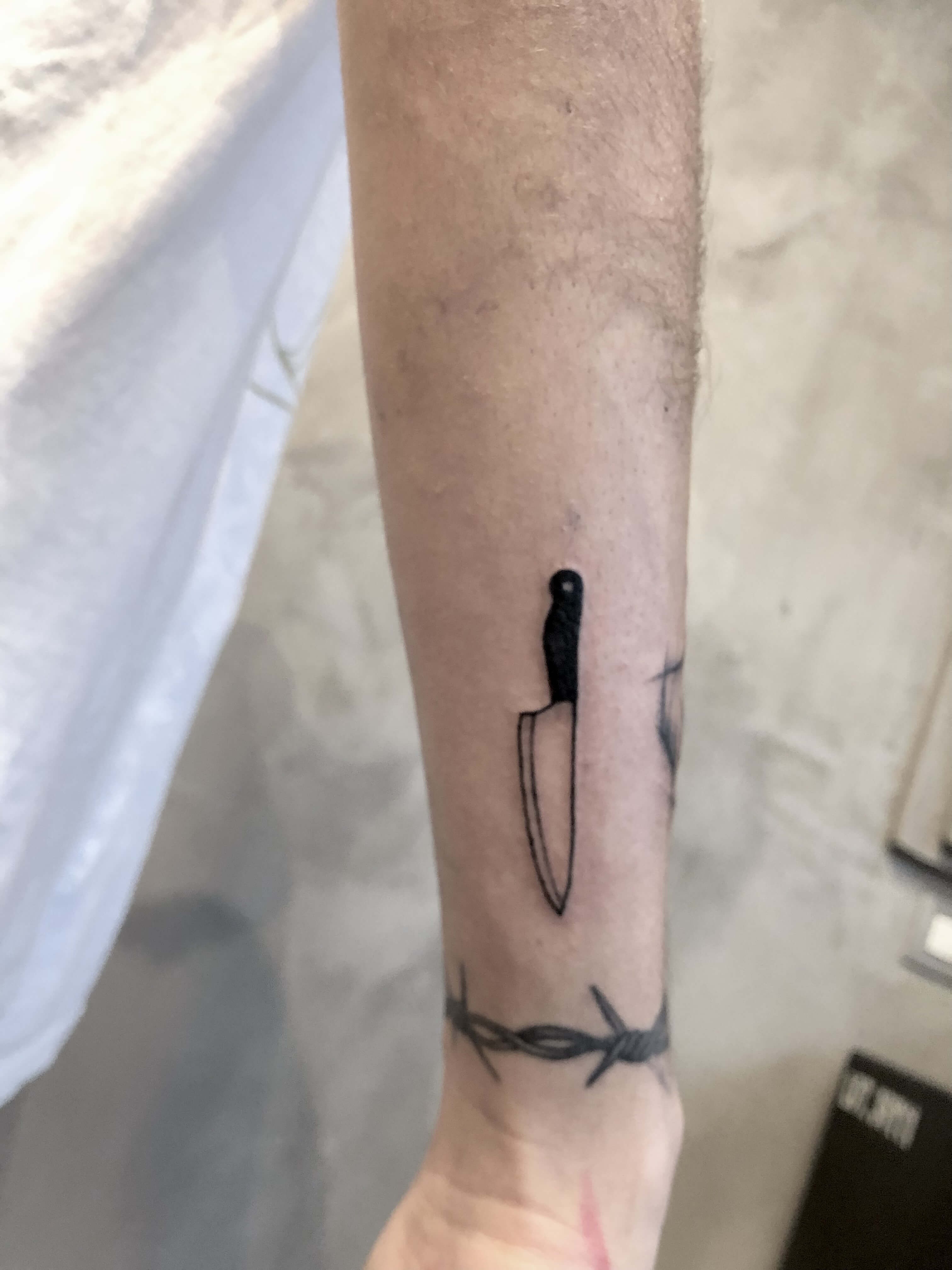 Mini tatouage d'un couteau sur le bras d'un homme réalisé à bordeaux