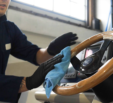 Young handsome professional guy (male) cleaner, washes the yacht after polishing and linin