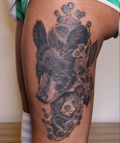 A black and gray thigh tattoo of a mama black bear above her baby surrounded by blackberries
