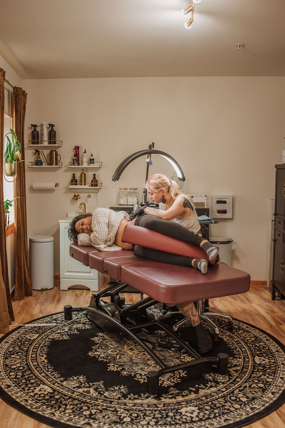 A female tattoo artist working on a tattoo on a woman's ribcage