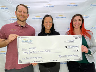 Three people standing in a row, all are smiling, and they are holding a large novelty check from Affordable Solar made out to WESST in the amount of $45,000.