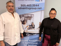 Luis is on the left, and a female employee is on the right, and in between is a stand up banner advertising Advantis Group Co.