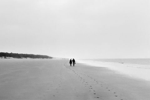 un homme et une femme marchent pieds nus sur une plage sans laisser de traces. Photo argentique de Claude Pavelek