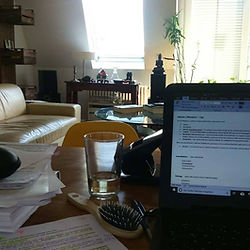 Online Arbeitsplatz mit aufgeklappten Laptop und Papier auf dem Schreibtisch