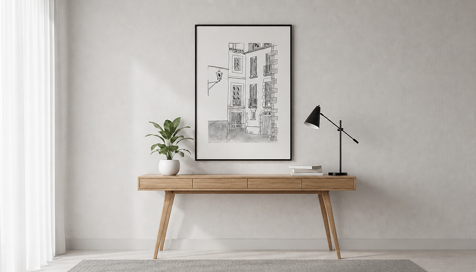 Modern interior with a wooden desk, a potted plant, books, a black lamp, and a framed building sketch. Soft lighting and neutral tones.