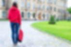 A student holding a backpack approaches the school entrance on the first day of school
