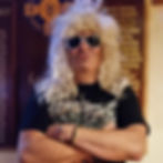 Man with blonde wig, sunglasses, Hard Rock shirt, arms crossed