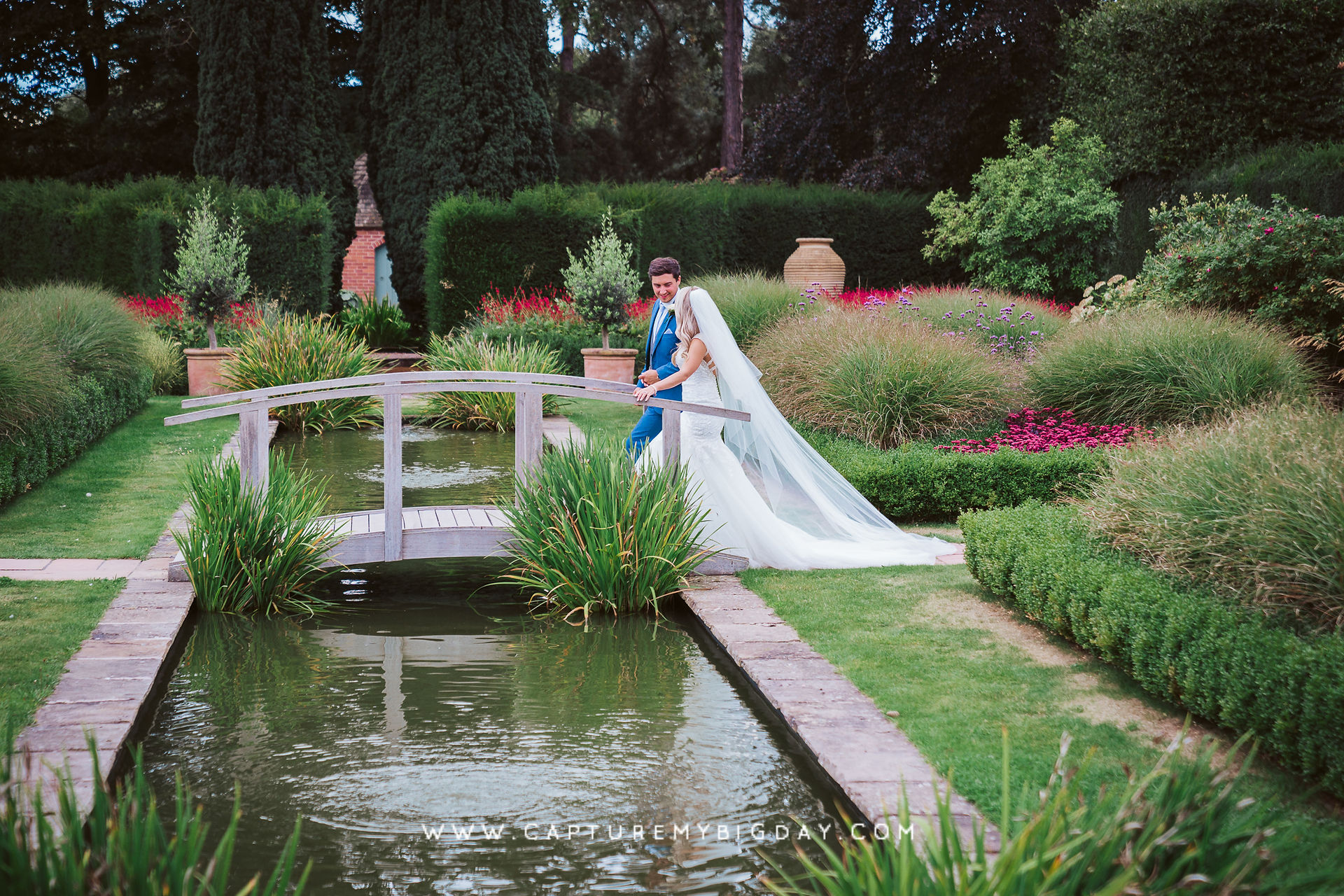 bride and groom walking over bride in garden