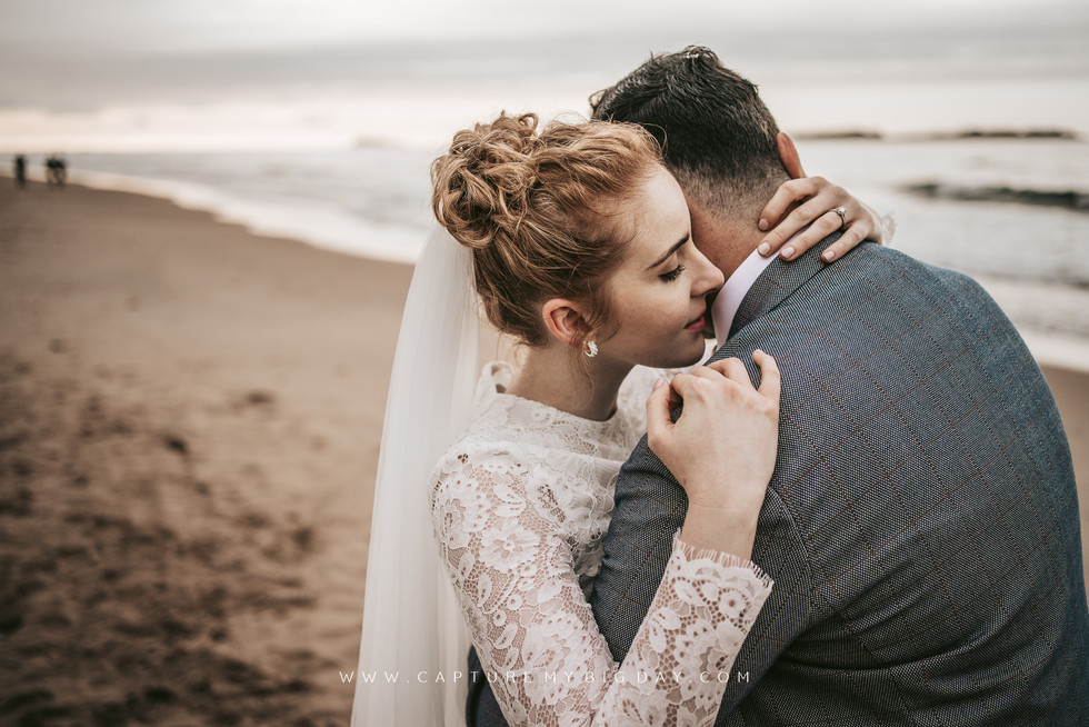 bride hugging the groom on the beach