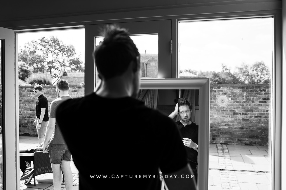 groom styling his hair in mirror