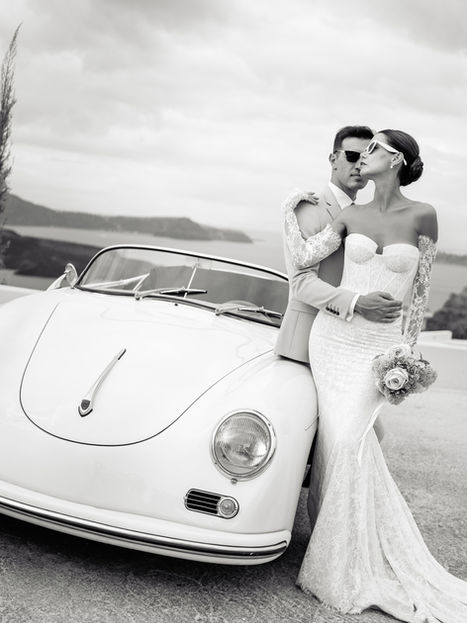 Bride and groom against car in Santorini