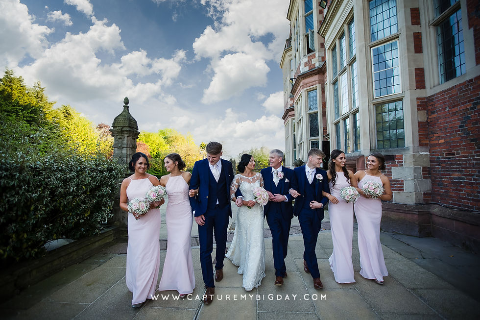 Wedding party walking in a line outside Crewe hall