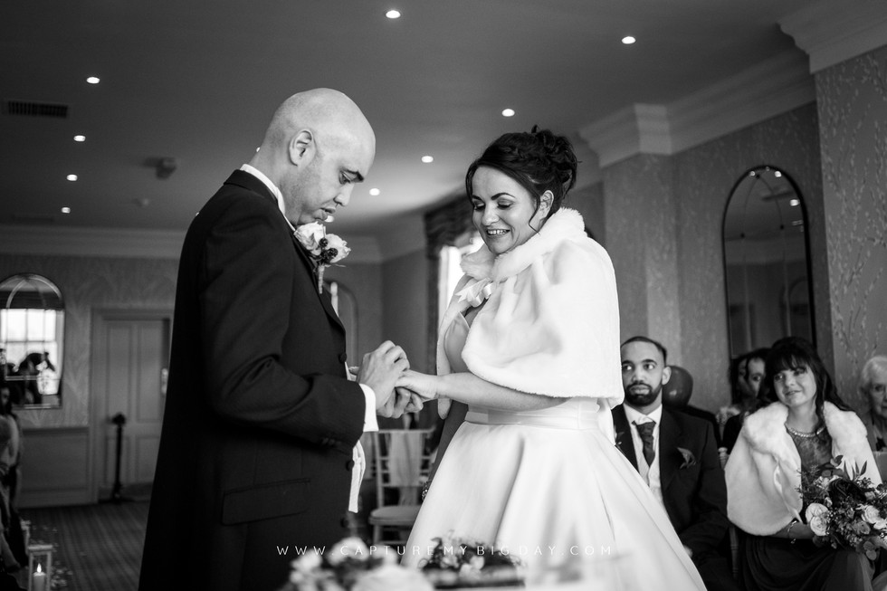 groom saying vows while placing ring on brides finger