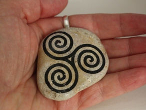 Stone with three spirals painted on it and held in someone's palm.