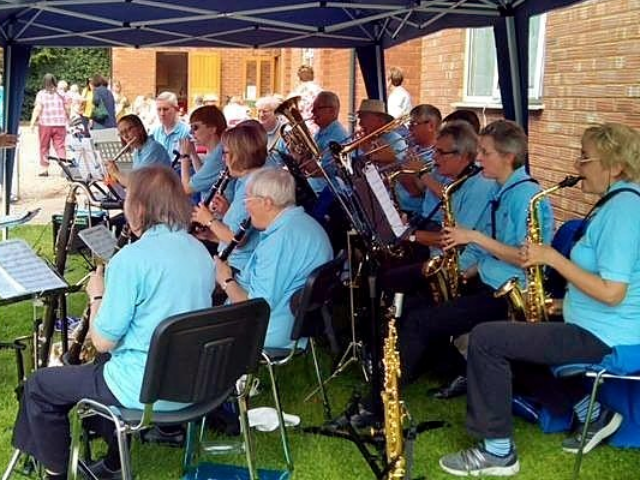 A woodwind band playing music in front of a crowd.