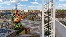 An emergency responder rappels from a crane platform as part of a simulated tower crane rescue on an active construction site in London. The exercise showcases safety procedures, emergency preparedness, and coordinated response in high-risk urban construction environments.