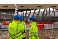 Group of construction workers discuss work at their site next to the hangers at Heathrow Airport.