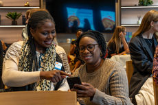 Two professional women networking and sharing contact details at a breakfast event in London
