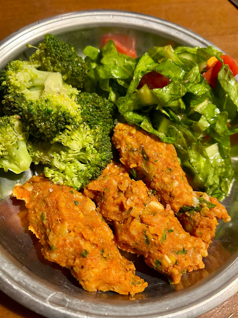 Turkish vegan lentil patties (mercimek köfte) served on lettuce leaves with fresh herbs, accompanied by a light salad and steamed broccoli drizzled with olive oil, lemon juice, and garlic.