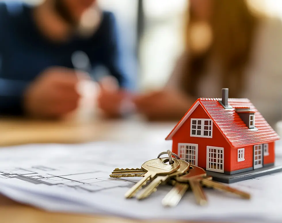 Toy red house and keys on blueprint; blurred people in background. Focus on model house, suggesting real estate or home buying.