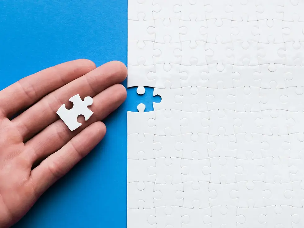 Hand holding a white puzzle piece above a nearly completed puzzle against a blue background, with one piece missing, creating a sense of anticipation.