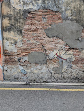 Boy holding lead of a dog/monster art work on a brick wall