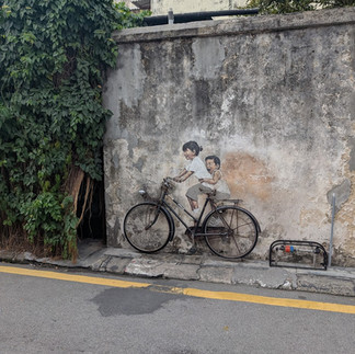 Two children on a bicycle art work on a wall 