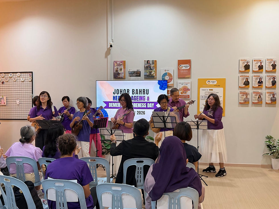 Seniors in purple sing and play ukuleles at a Johor Bahru healthy ageing and dementia awareness day event, audience seated.