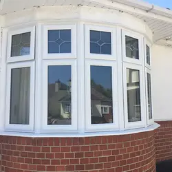 Triple white casement windows on red brick wall