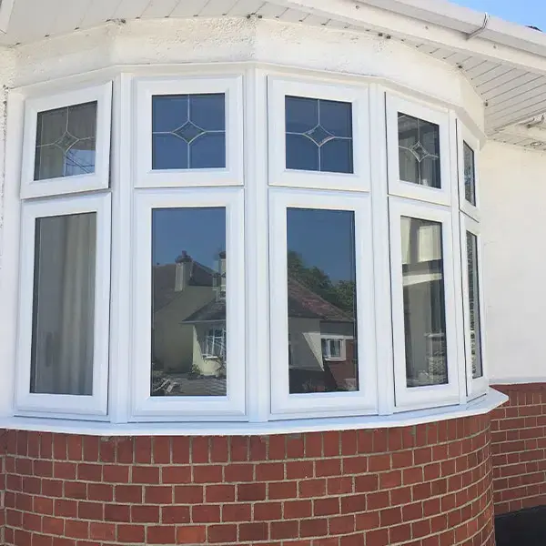 Triple white casement windows on red brick wall