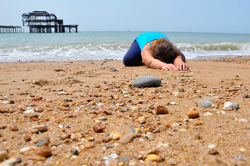 Child pose - outdoor yoga on Brighton beach in front of the old pier
