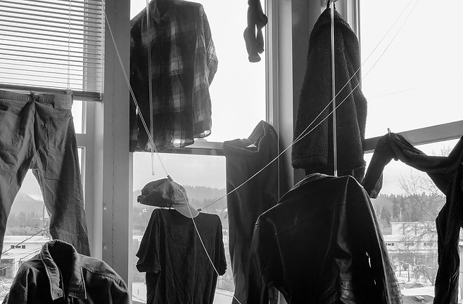 black and white photo of the inside of windows with clothes aranged in several places to appear hanging or floating