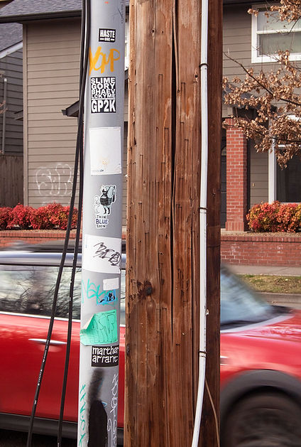 A Telephone poll with stickers on a pipe attached to it