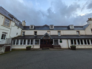 A large white building making the Sligachan Hotel a great place to stay when viewing the things to see and do in Skye