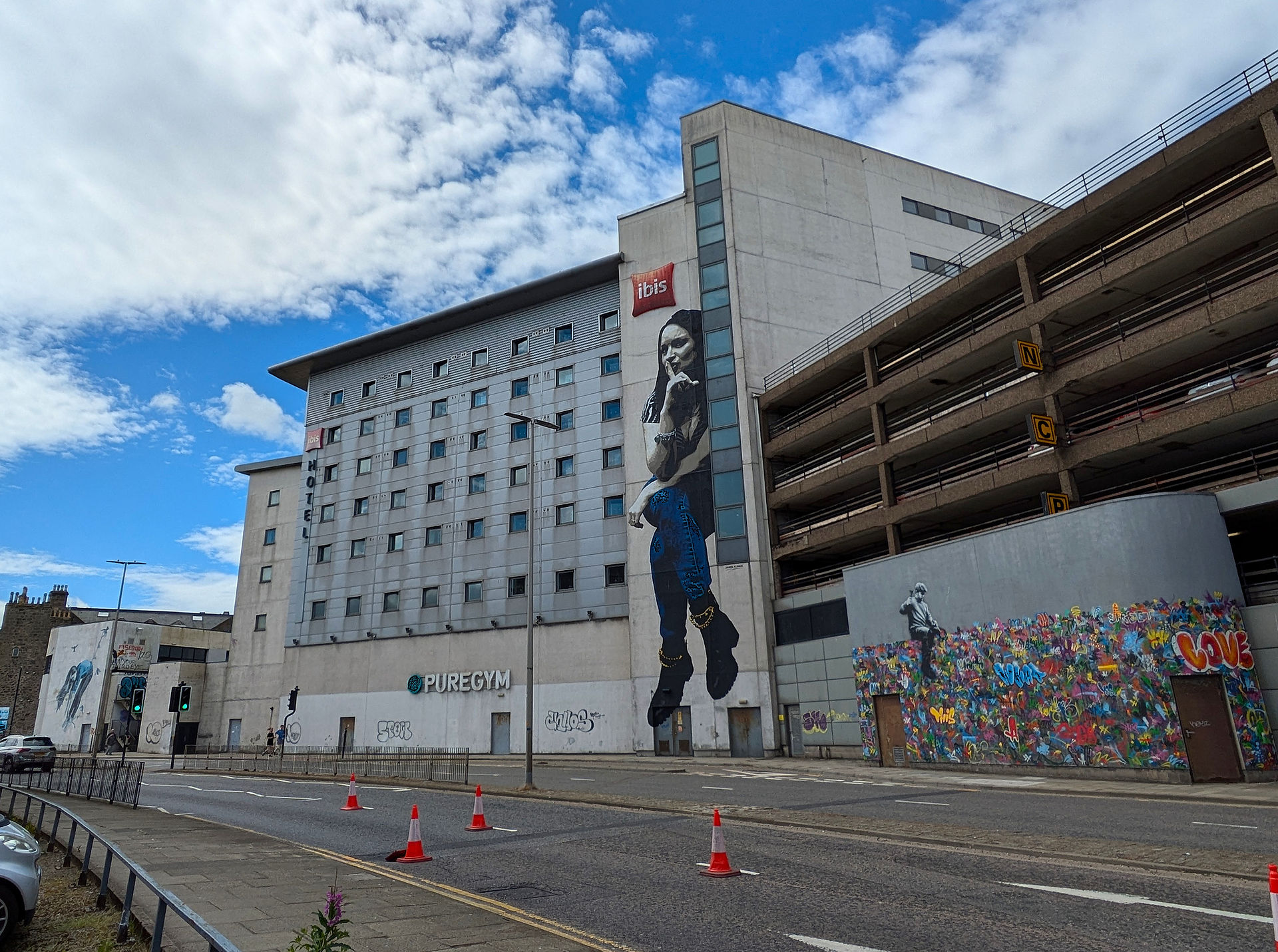 One of the Aberdeen street art murals on a building depicting a woman sitting.