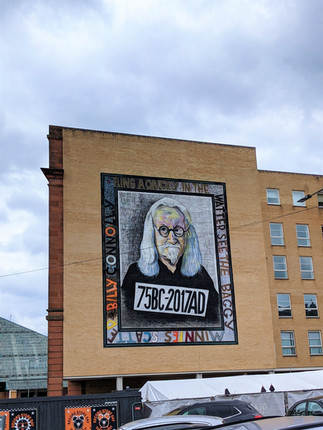 Street art murals of a portrait of Billy Connolly in a frame.