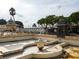 A sunny courtyard surrounded by trees, making it one of the attractions you should visit in Udaipur, India