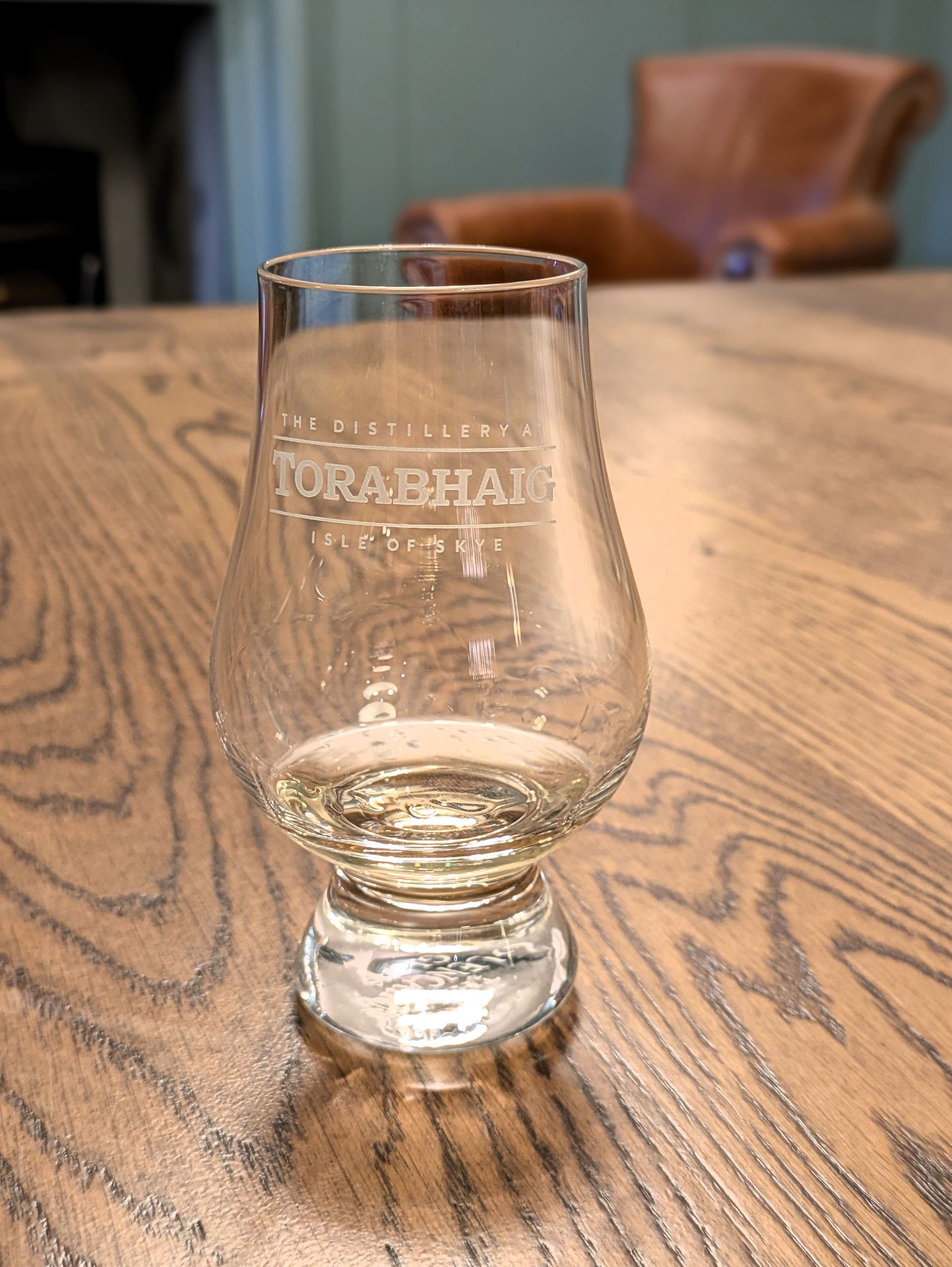 A wee dram of whisky in a tasting glass sat on a wooden table making Torabhaig Distiller one of the best things to see and do in Skye