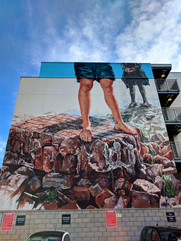 One of the Aberdeen street art murals on a building depicting figures standing on rocks.