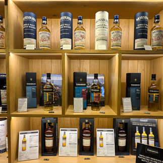 A wooden shelving unit displaying bottles of whisky making the Torabhaig Distiller one of the best things to see and do in Skye