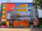 Colorful mural-covered building with graffiti gate, bold geometric blocks, a painted face, and the word WALALA on the upper wall. Street Art Murals of London