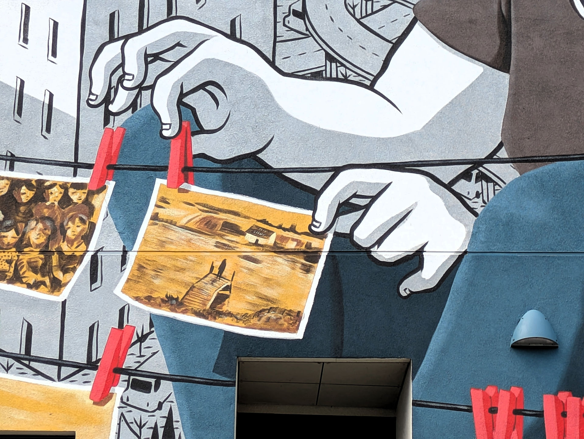 One of the Aberdeen street art murals on a building depicting a young woman pegging photographs to a clothes line.