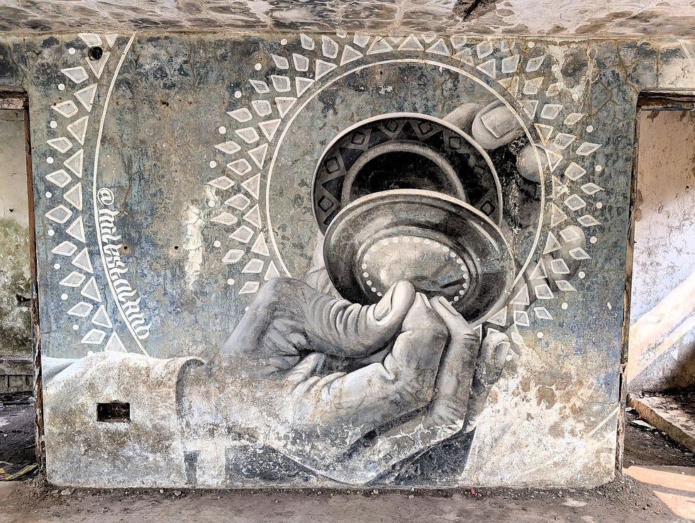 Wall mural of hands holding a vessel with geometric patterns on a weathered surface, featuring muted colors and the text @elviskrub. Places to see in rishikesh.