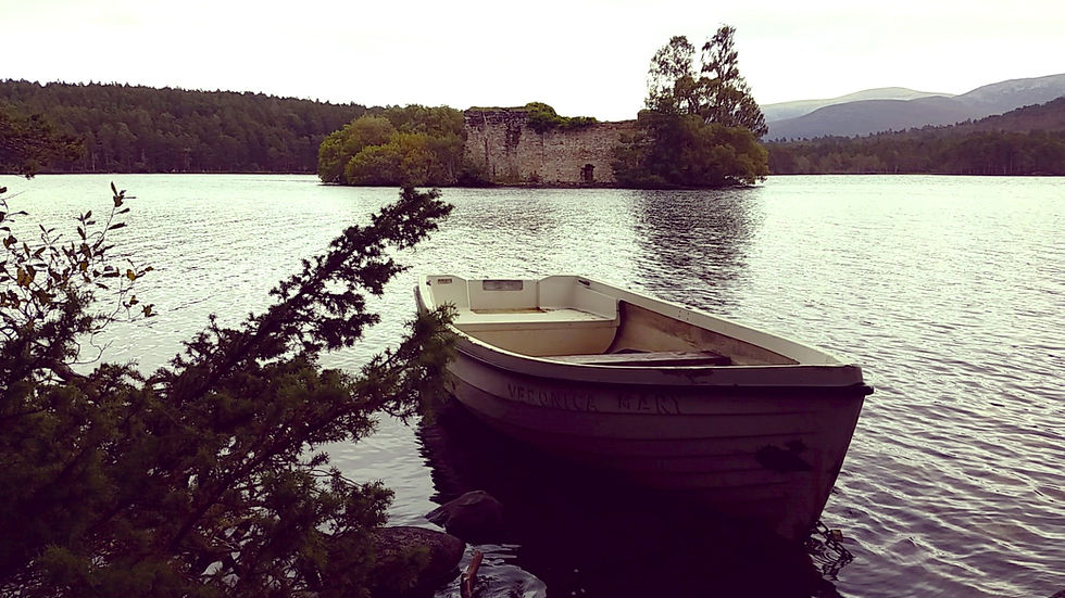 Boat named "Veronica Mary" on a calm lake, with ruins and trees in the background. Overcast sky creates a serene, peaceful mood. Things to do at Aviemore in Scotland.