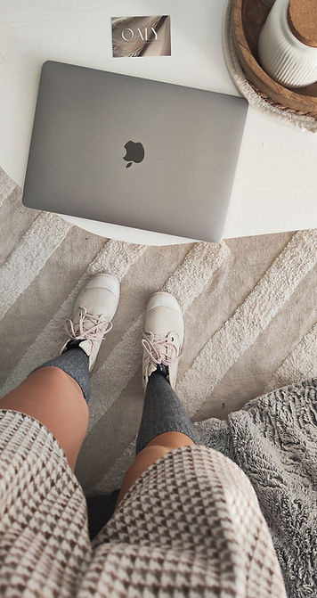 Image de mon mac avec une carte de visite OALY posée sur une table basse blanche. Photo prise de haut, on voit mes jambes