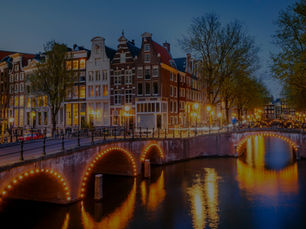 Amsterdam canals at night with illuminated bridges and canal houses