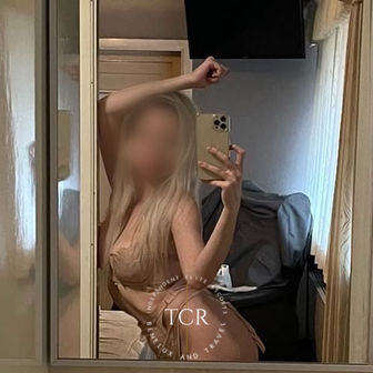 Emily - Verified mirror selfie holding a phone in a warm wood-panelled setting