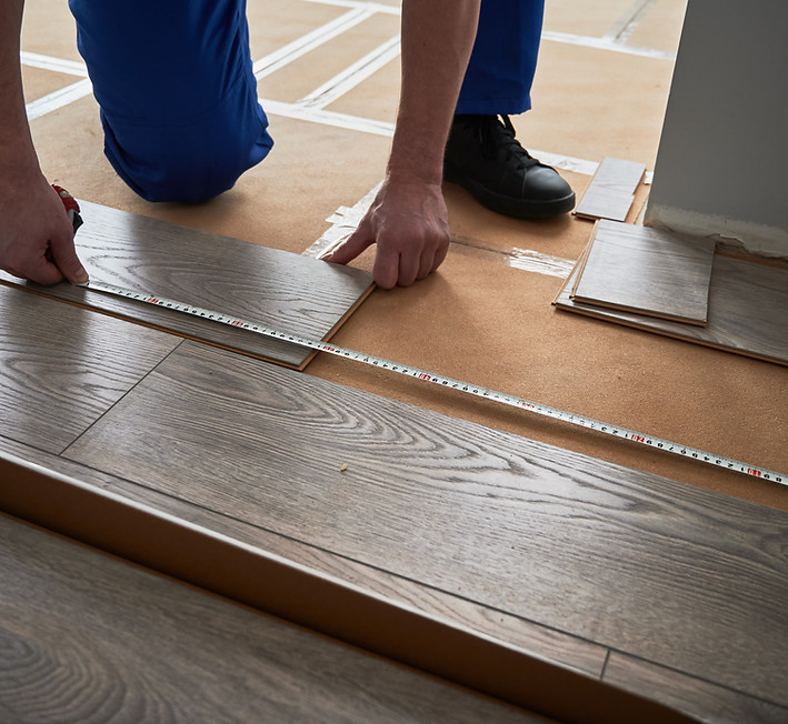 Worker installing grey wood-look floor tiles
