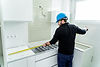 Contractor measuring kitchen cabinets during renovation